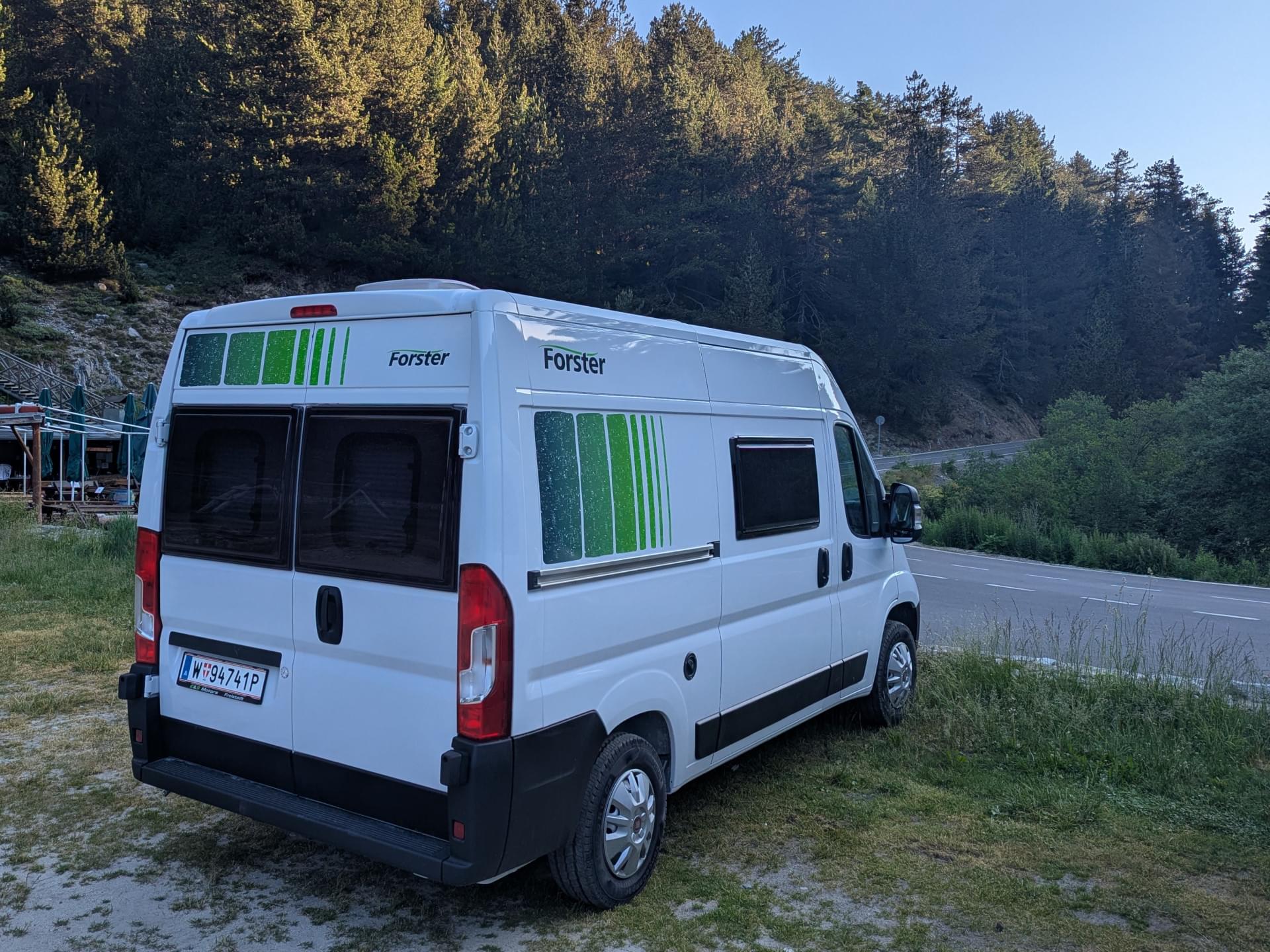 Ein weißes Wohnmobil auf Gras nahe einer Straße geparkt.